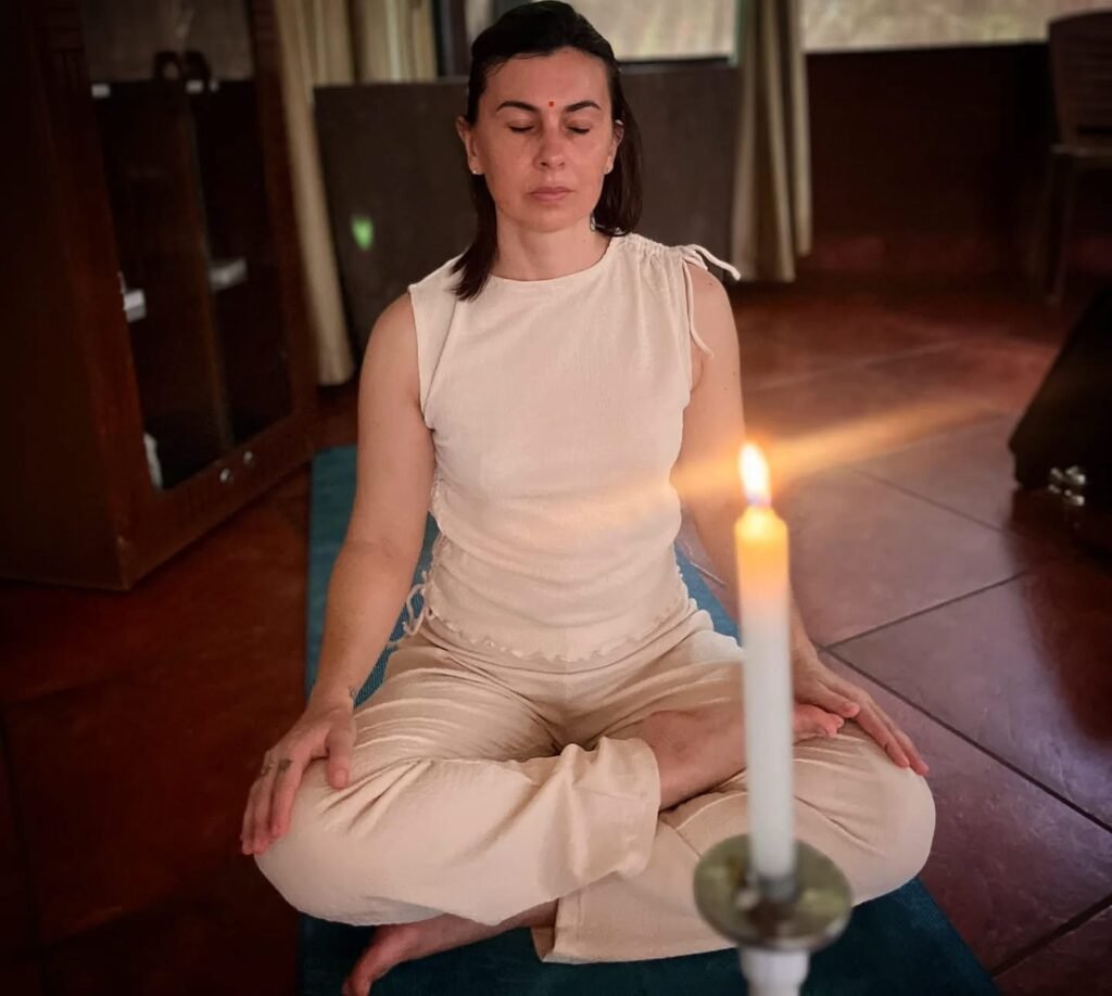 Yoga therapist meditating in lotus pose (Padmasana) with bindi, candlelight meditation practice, IndiaYoga therapist meditating in lotus pose (Padmasana) with bindi, candlelight meditation practice, India